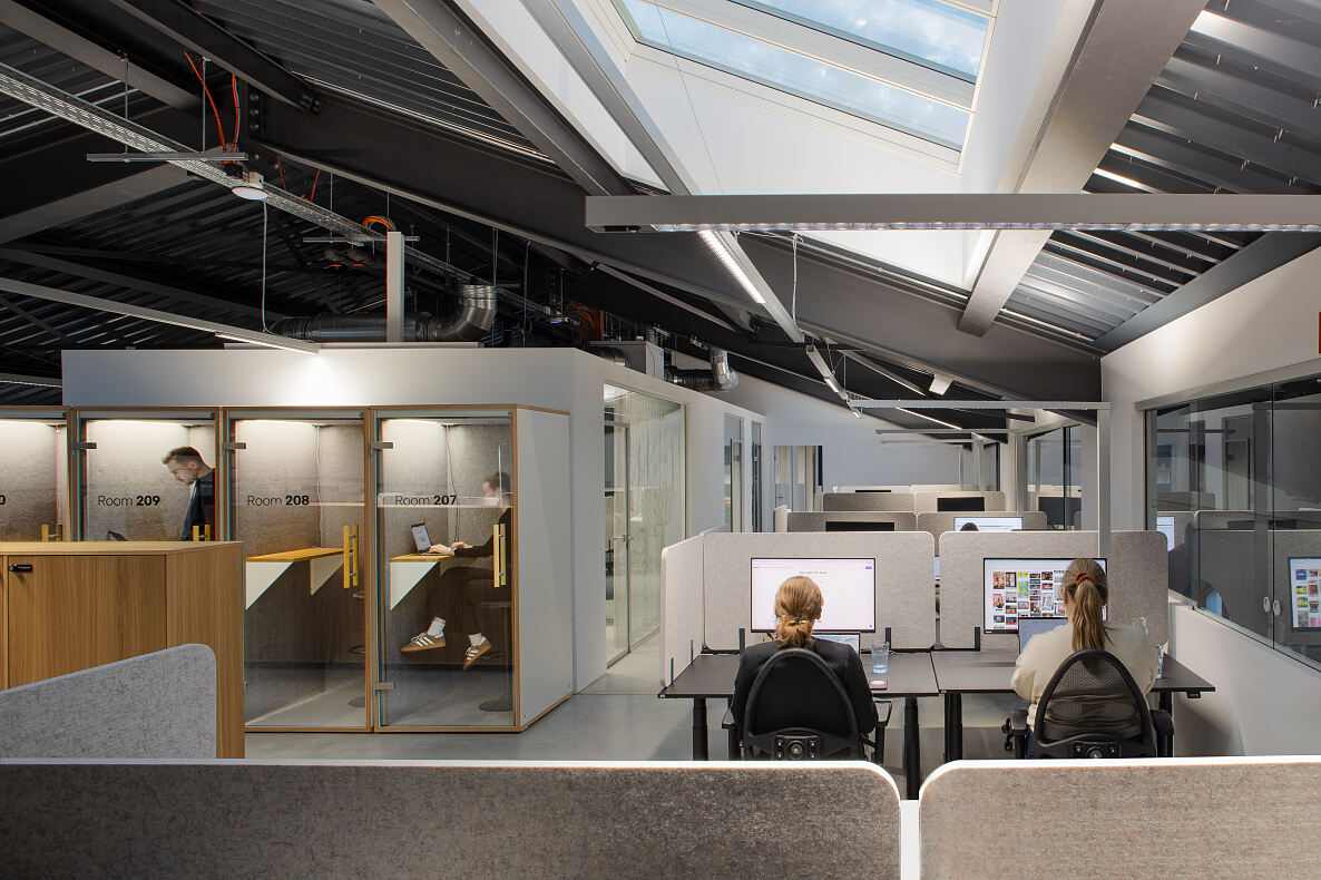 Rückzugsorte für konzentriertes Arbeiten: Telefonboxen und ruhige Arbeitsbereiche im Neubau unterstützen fokussierte Einzelarbeit im Arbeitsalltag.