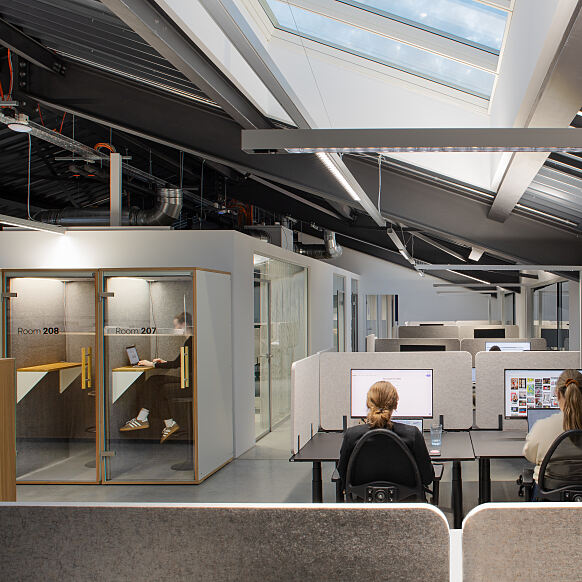 Rückzugsorte für konzentriertes Arbeiten: Telefonboxen und ruhige Arbeitsbereiche im Neubau unterstützen fokussierte Einzelarbeit im Arbeitsalltag.