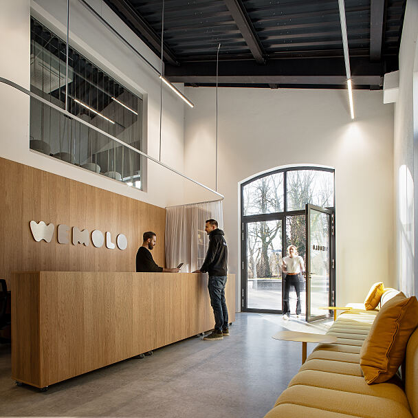 Ankommen im neuen Wemolo-Standort in München-Thalkirchen: Der Empfangsbereich in der denkmalgeschützten Triebwagenhalle dient als zentrale Schnittstelle für Mitarbeitende und Besucher.