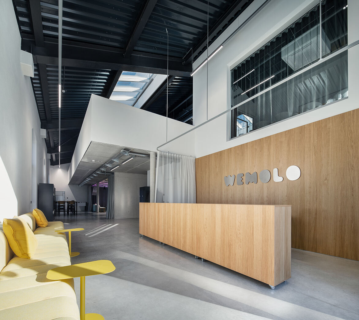 Empfangsbereich im neuen Wemolo-Headquarter im Isarwinkel: Die historische Triebwagenhalle verbindet offene Raumstrukturen mit modernen Arbeitsflächen für Austausch und Zusammenarbeit.