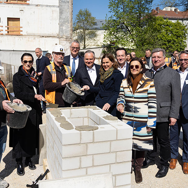 Personen auf dem Bild von links nach rechts: Implenia, Rita Ahlers, Partnerin und Architektin bei Hilmer Satller Architekten; Implenia; Constantin H. Alsheimer, Vorstandsvorsitzender der THÜGA; Dr. Christian Scharpf, Referent für Arbeit und Wirtschaft; Verena Dietl, Dritte Bürgermeisterin von München; Stadtbaurätin Prof. Dr. (Univ. Florenz) Elisabeth Merk; Christian Lealahabumrung, Grüner und Gesellschafter der Rock Capital Group; Christian Bernreiter, Staatsminister für Wohnen, Bau und Verkehr; Andreas Wißmeier, Geschäftsführer der Rock Capital Group.  