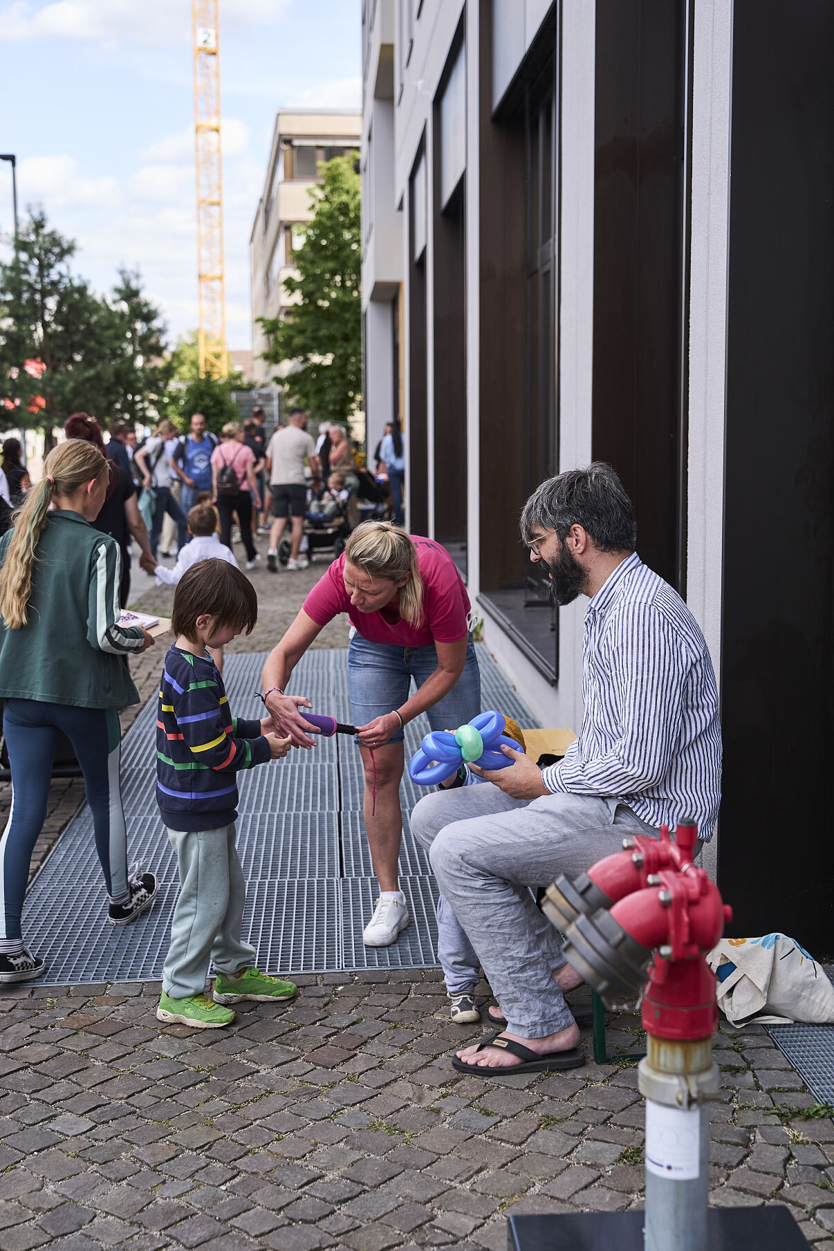 ```text Eine Ballonkünstlerin formt Figuren für die Kinder beim Familienfest zur Kita-Eröffnung.