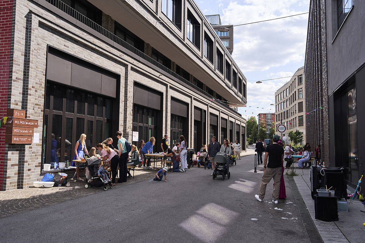 Das Familienfest erstreckt sich entlang der Quartiersstraße der Macherei München und verbindet Kita, Gastronomie und Nachbarschaft.