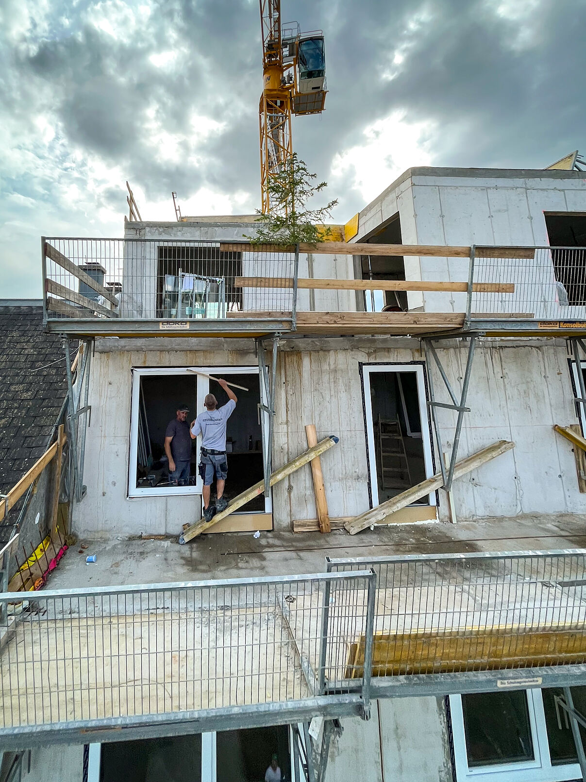 Arbeiter beim Einbau von Fenstern in den obersten Stockwerken, die den Fokus auf Wetterfestigkeit legen