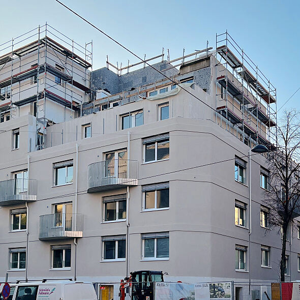 Die Fassade des Wohnbauprojekts Kh:Ek:51 in der Khekgasse und Korbgasse zeigt modernes Design kurz vor Fertigstellung, Gerüste sind noch sichtbare Zeichen der laufenden letzten Arbeiten.