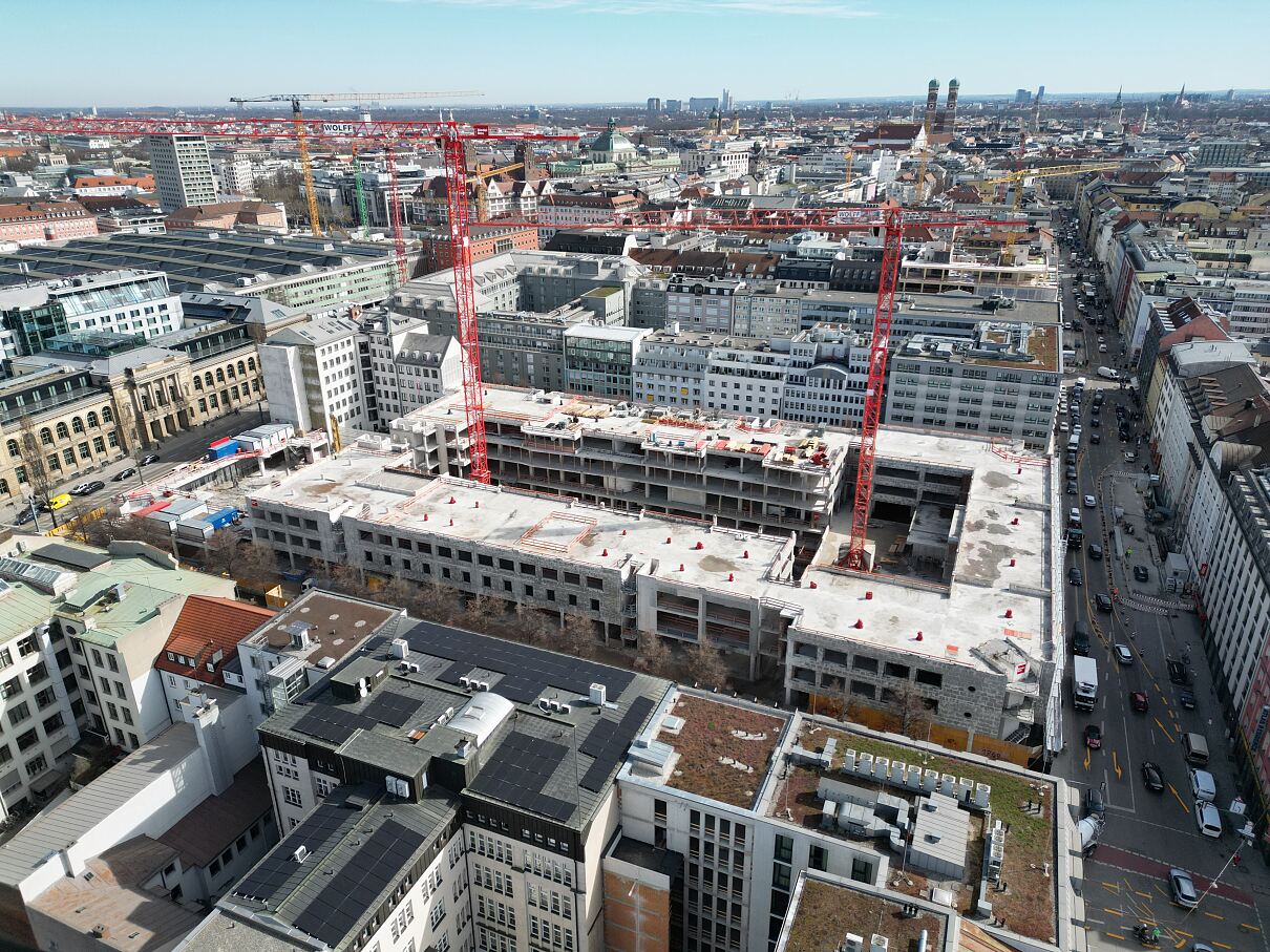 Luftaufnahme der Baustelle von THE VERSE: Im Herzen der Münchner Innenstadt entsteht auf sechs Vollgeschossen und zwei Staffelgeschossen ein Mixed-Use-Quartier mit über 70.000 m² Mietfläche und Raum für mehr als 3.500 Arbeitsplätze.