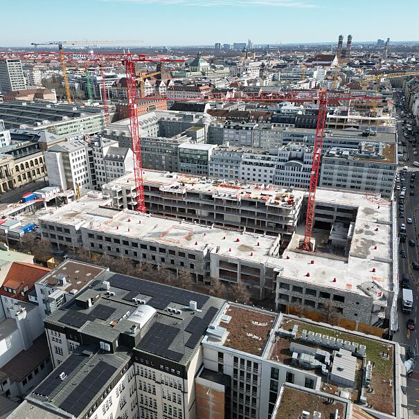 Luftaufnahme der Baustelle von THE VERSE: Im Herzen der Münchner Innenstadt entsteht auf sechs Vollgeschossen und zwei Staffelgeschossen ein Mixed-Use-Quartier mit über 70.000 m² Mietfläche und Raum für mehr als 3.500 Arbeitsplätze.