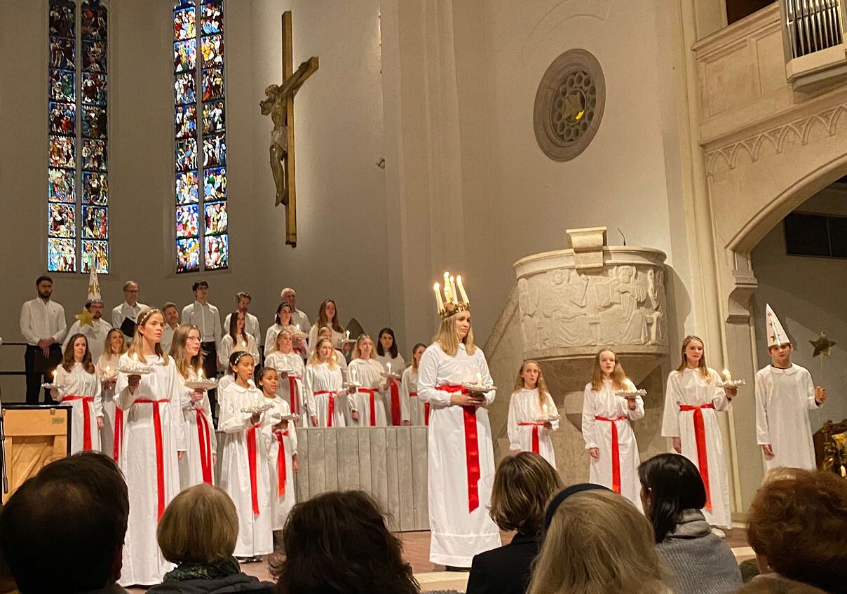 Das Ensemble beim Luciafest 2022 in der St. Matthäus-Kirche, mit weißen Gewändern und Lichterkronen.